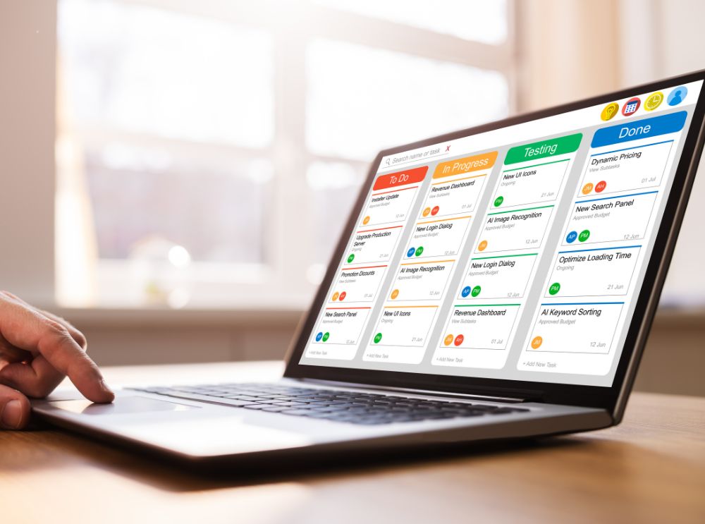 Notebook aberto em uma mesa, exibindo um painel Kanban com colunas "To-Do", "In Progress", "Testing" e "Done", usado para organização e gestão de tarefas.